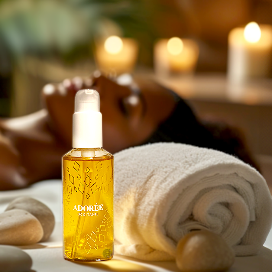 Flacon Adorée posé avec serviette et bougie dans ambiance spa